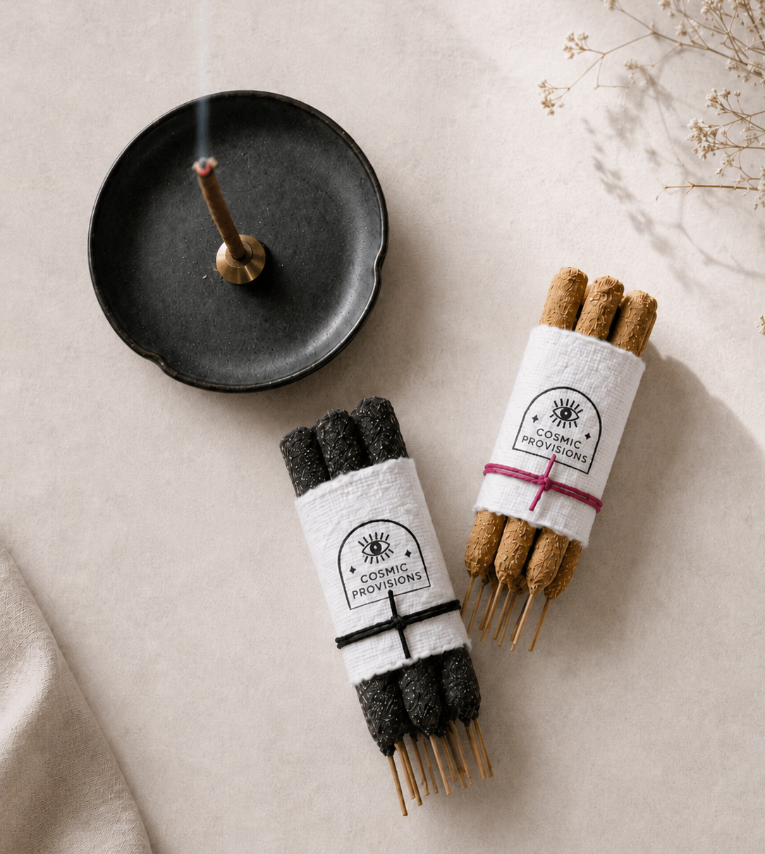 Palo Santo incense stick burning in brass holder sitting on a black ceramic dish shown with handrolled incense bundles — Cosmic Provisions